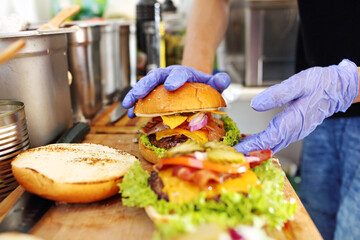 Making burgers. Preparing a hamburger in a protective gloves, in a food truck, in a fast food restaurant, close up.