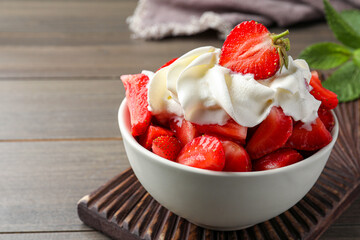 Delicious strawberries with whipped cream served on wooden table, closeup