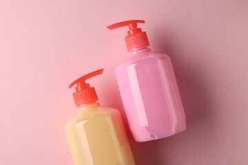 Bottles of liquid soap on pink background, flat lay