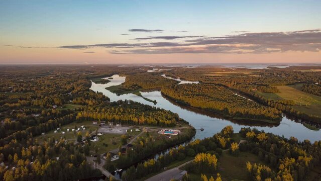 Hyperlapse drone shot of a vibrant sunset sky with clouds, moving over islands on the Tornionjoki river in Lapland