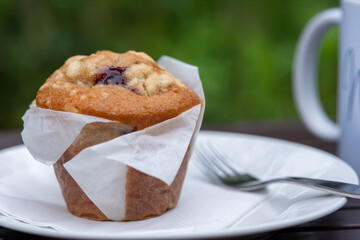 Freshly made blueberry muffin served on a plate outdoors.