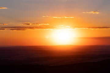 View from Feldberg mountain in Hessen, Germany. Wide landscape with hills and clouds during sun goes down.