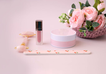 Obraz na płótnie Canvas On a pink background, a jar of cream, a facial massager, flowers, a nail file, a shopping list