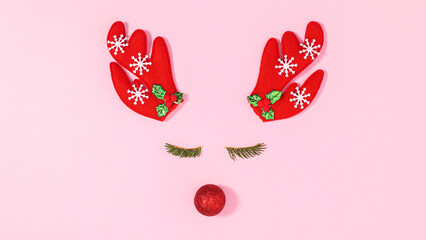Creative reindeer made with ornaments on pastel pink background. FLat lay
