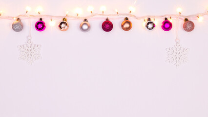 Creative garland with Christmas lights and ornaments hanged on white background. Flat lay