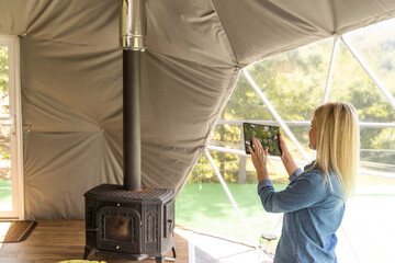 woman holding a tablet with the smart home application in a glamping dome tent domestic © Angelov