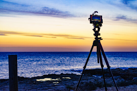 Camera taking picture of sunrise over sea