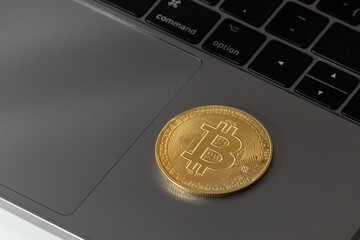 Bitcoin cryptocurrency coin over a grey laptop. Decentralized virtual money, blockchain technology.