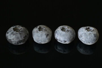 Closeup of four blueberries with reflections