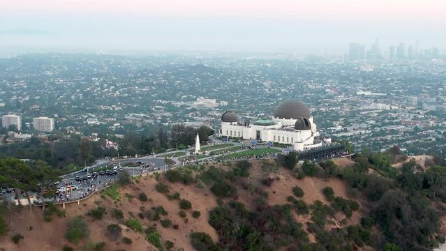 Amazing rising reveal over Griffith Observatory, sprawling crowded cityscape. Aerial ascending.