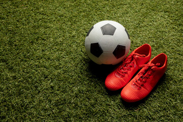 Composition of football and shoes over sports stadium and copy space