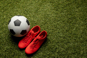 Composition of football and shoes over sports stadium and copy space