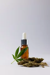 Poster Vertical image of bottle of cbd oil and marihuana leaf on white surface © vectorfusionart