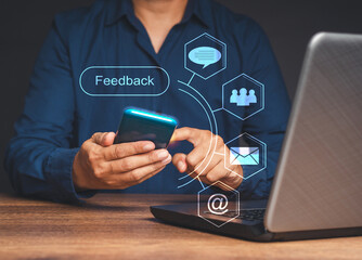 Man using a smartphone to give feedback via the Internet while sitting at the table in the office