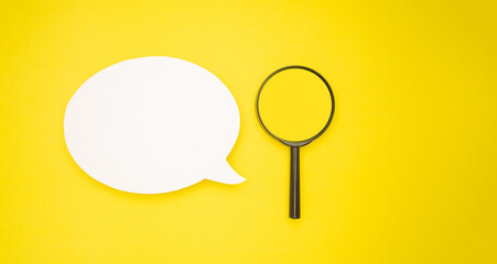 Top view of a blank white speech bubble and a magnifying glass isolated on a light green background