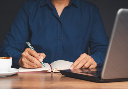 Businessman in a blue shirt signing on lease contract or agreement while sitting in the office