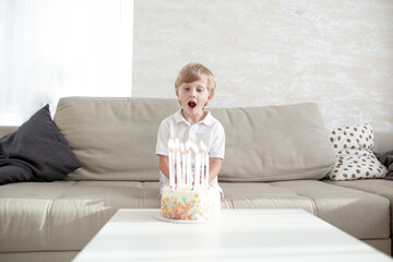 The kid blows out the candles in the birthday cake at home