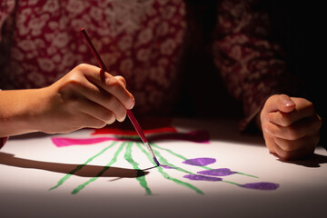 Happy young girl in art studio painting picture.  Selective focus on hand.  Horizontal image.