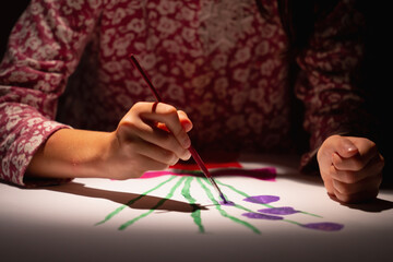 Happy young girl in art studio painting picture.  Selective focus on hand.