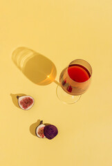 Minimal party concept with a glass of red wine and fig slices on sunny day. Fruits and red drink on...