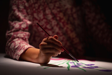 Happy young girl painting with paints color and brush. Selective focus on hand.