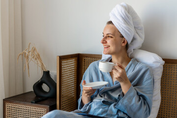 a young woman in a blue bathrobe and a white towel on her head lies on the bed of a hotel room and...