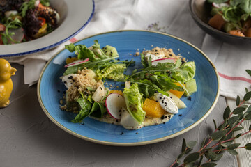 Radish, onion and orange salad with lettuce on blue plate on the table