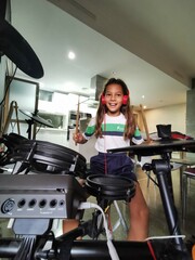 Happy girl with headphones playing a percussion instrument such as the drums. Solfeggio and music lessons