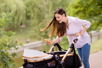 Photo of modern mommy lady blogger leisure weekend walk make picture infant son sleep in pram outside