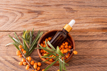 a bottle dropper with a cosmetic based on sea buckthorn oil for facial skin care lies in a wooden...