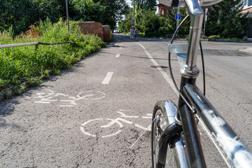 Bicycle on a separate bike path with painted white bike signs and markings on a car road in the city.