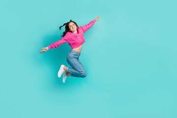 Full length photo of gorgeous adorable woman dressed pink sweater jeans sneakers flying arms plan wings isolated on teal color background