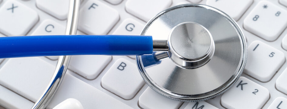 Blue stethoscope on laptop computer keyboard, medical design concept.