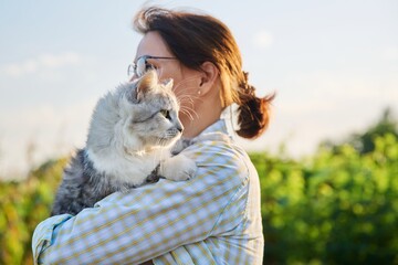 Outdoor portrait of middle aged woman with cat in her arms