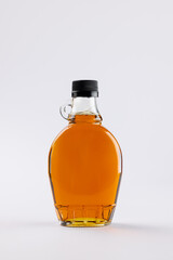 Vertical image of glass bottle of maple syrup on white background, with copy space © vectorfusionart
