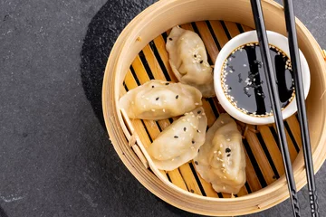 Foto op Aluminium Overhead view of asian dumplings, soy sauce and chopsticks in wooden dish on grey background © vectorfusionart