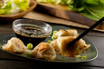 Foto op Aluminium Close up of asian dumplings, soy sauce and chopsticks with plate and wooden background © vectorfusionart