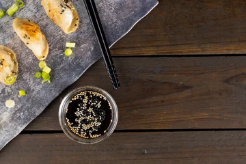 Foto op Aluminium Overhead view of asian dumplings, soy sauce and chopsticks with slate and wooden background © vectorfusionart