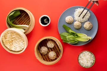 Foto op Aluminium Overhead view of asian dumplings, soy sauce, endive, rice and chopsticks on red background © vectorfusionart