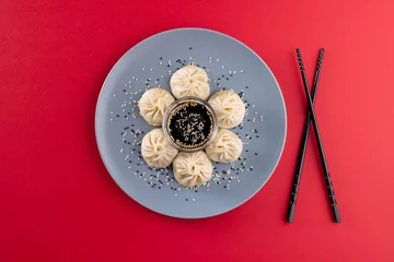Foto op Canvas Overhead view of asian dumplings, soy sauce and chopsticks on red background © vectorfusionart