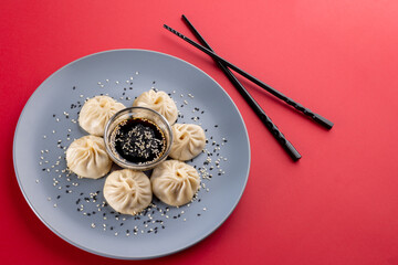 Overhead view of asian dumplings, soy sauce and chopsticks on red background