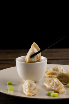 Close up of asian dumplings, soy sauce and chopsticks on plate and wooden background