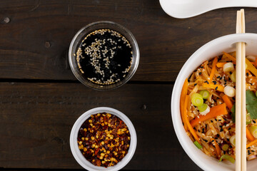 Overhead view of asian wok stir fry noodles and chopsticks and condiments on wooden background