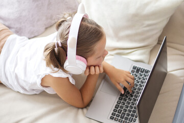 A schoolgirl girl lies on the couch listening to music
