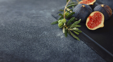 Obraz na płótnie Canvas fresh ripe figs fruit and olive branch on dark table. mediterranean food concept