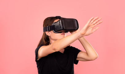 Woman wearing a virtual reality headset, pink background.