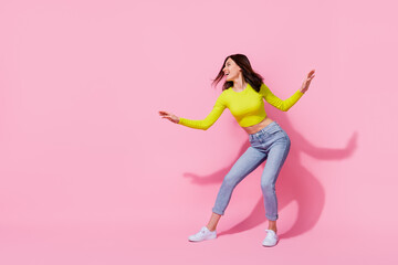 Photo of adorable funny girl dressed lime shirt dancing looking empty space isolated pink color...