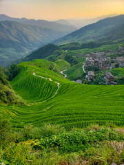 Fototapeta na wymiar A magical photo of a mountain landscape in the fog. A village on the slopes. Winding roads. Terraced fields. China.