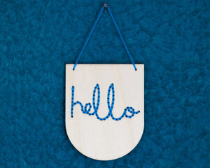 Hello sign hanging by string and nail on blue bathroom wall