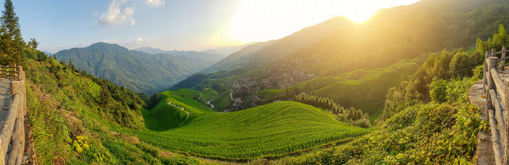 A magical photo of a mountain landscape at sunset. A village on the slopes. Winding roads. Terraced fields. China.